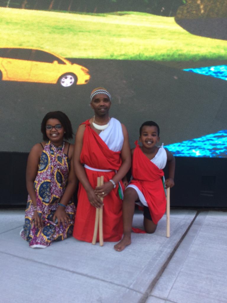 A performer with two young family members in traditional dress at an outdoor event