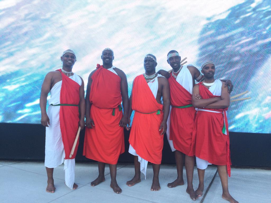 Five ensemble members in traditional dress on an outdoor stage